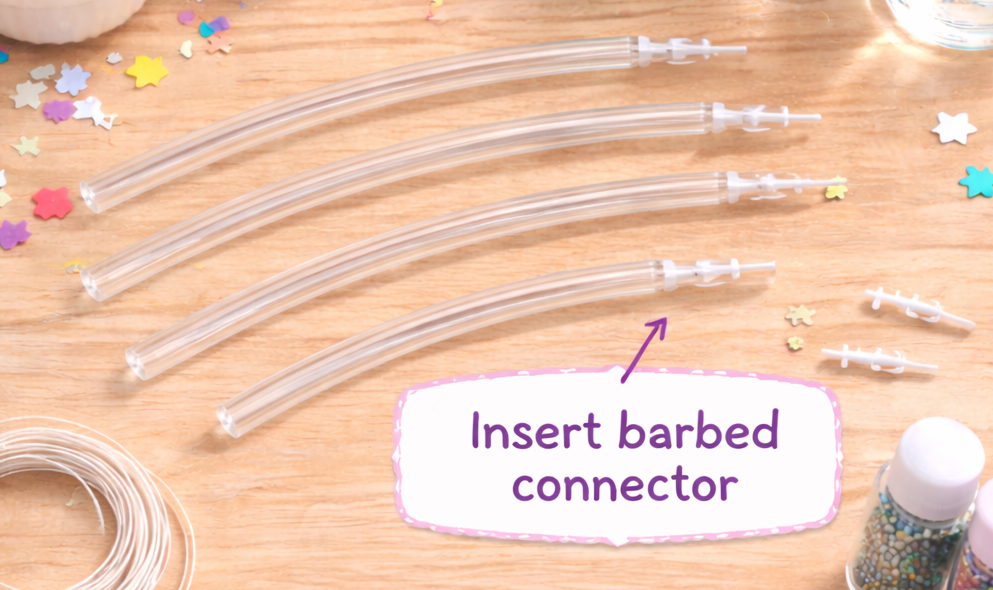 Inserting a barbed connector into clear plastic tubing to form a DIY glitter bracelet.