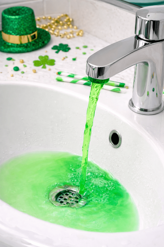 Bathroom faucet running green water from hidden food coloring for a St. Patrick’s Day leprechaun surprise.