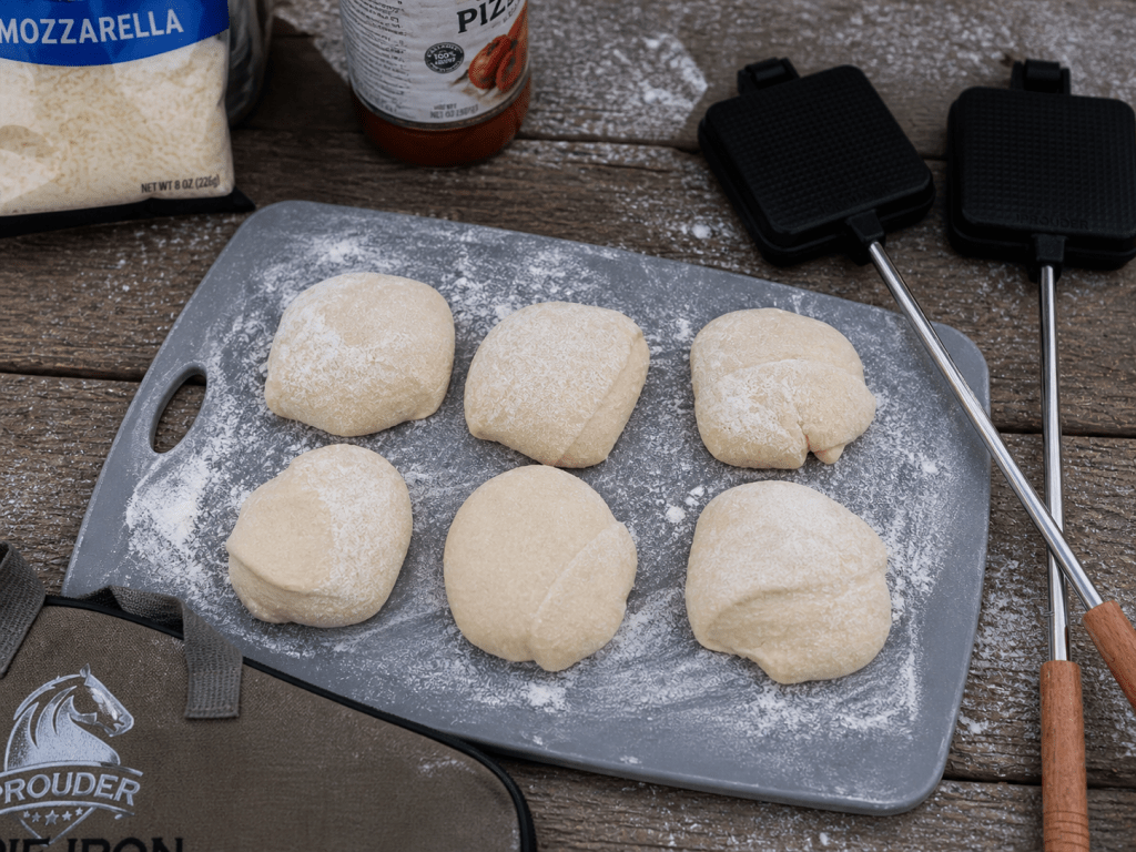 Pizza dough divided into small portions on a floured board for making campfire pizzas
